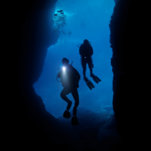 two divers deep in the sea, shining a light into a dark cavern, representing finding thought leadership inspiration by going deeper