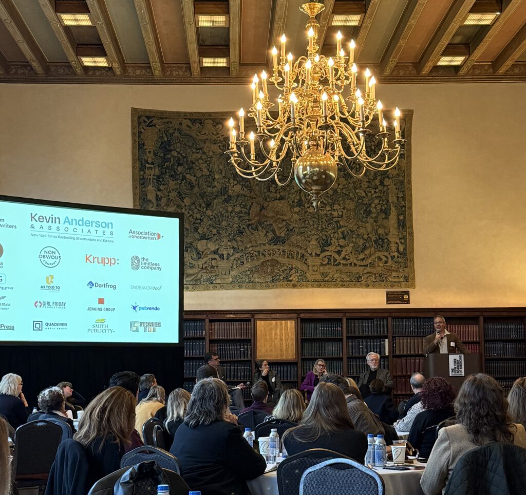 a group of people sitting in a fancy library in front of a stage of panelists
